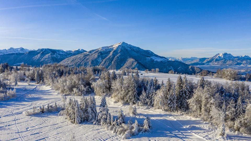 Langlaufloipe in der verschneiten Winterlandschaft mit der Rigi und dem Pilatus im Hintergrund.